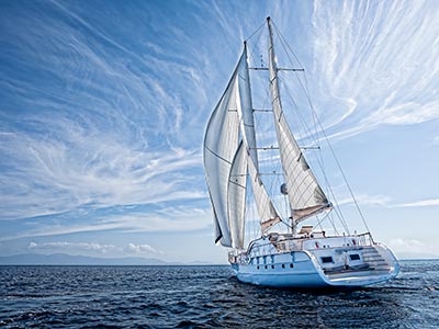 Large white boat with huge sails on the water with clear skies