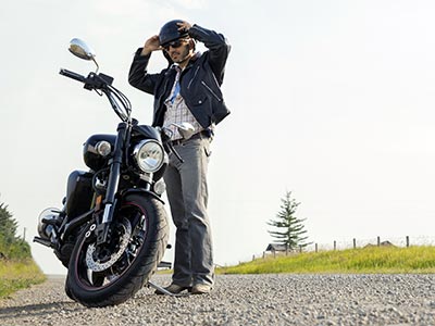 Man next to Harley motorcycle on side of the road