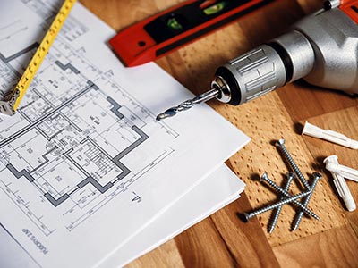 Drill, tape measure and building plans for construction