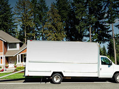 White moving truck outside of house in front of trees