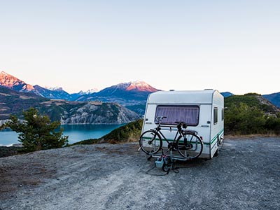 White RV with bike on back facing mountains